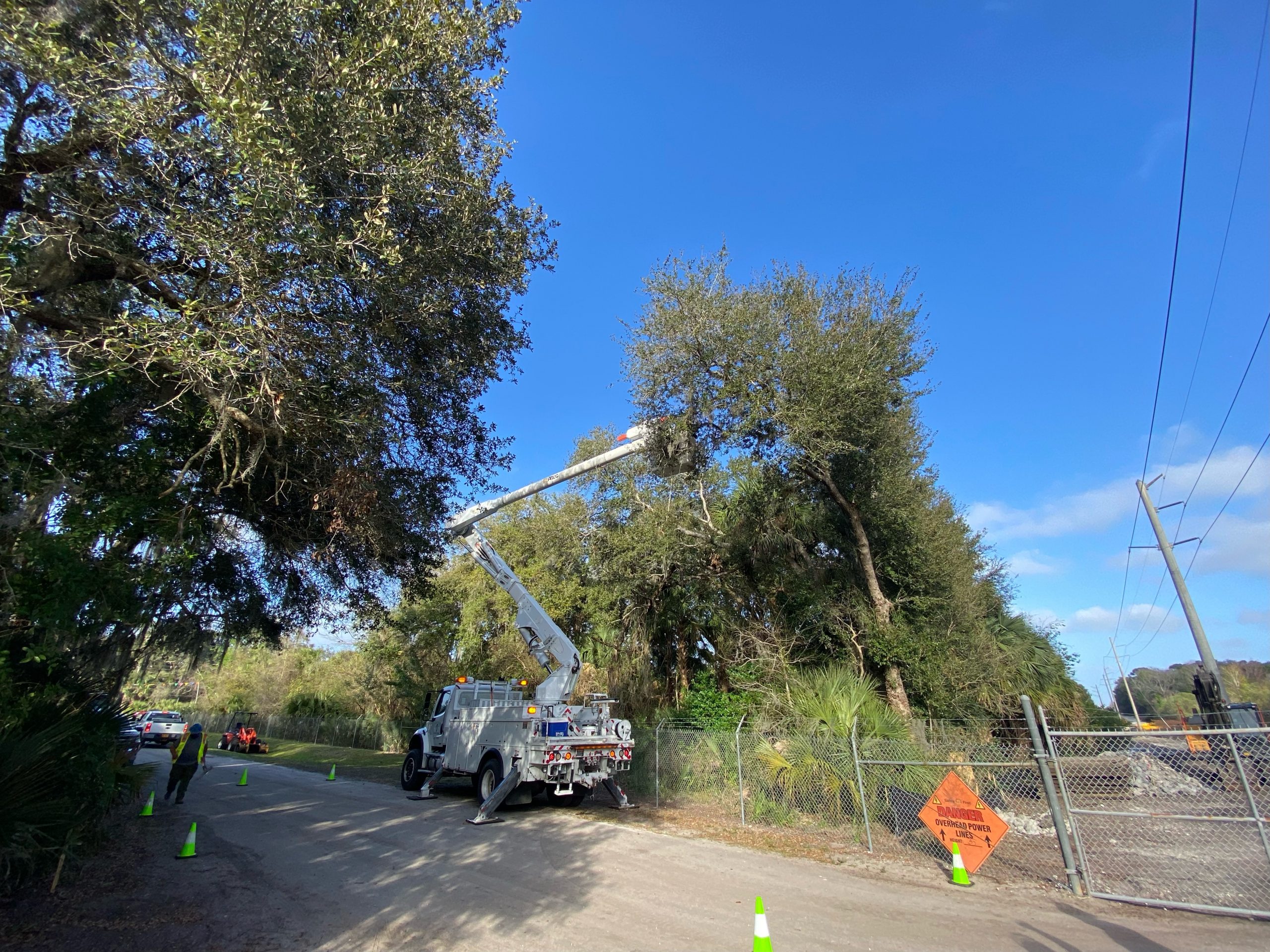 4x4 bucket truck with crew trimming roadside trees