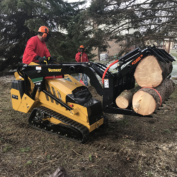 Vermeer mini skid carrying log rounds with grapple