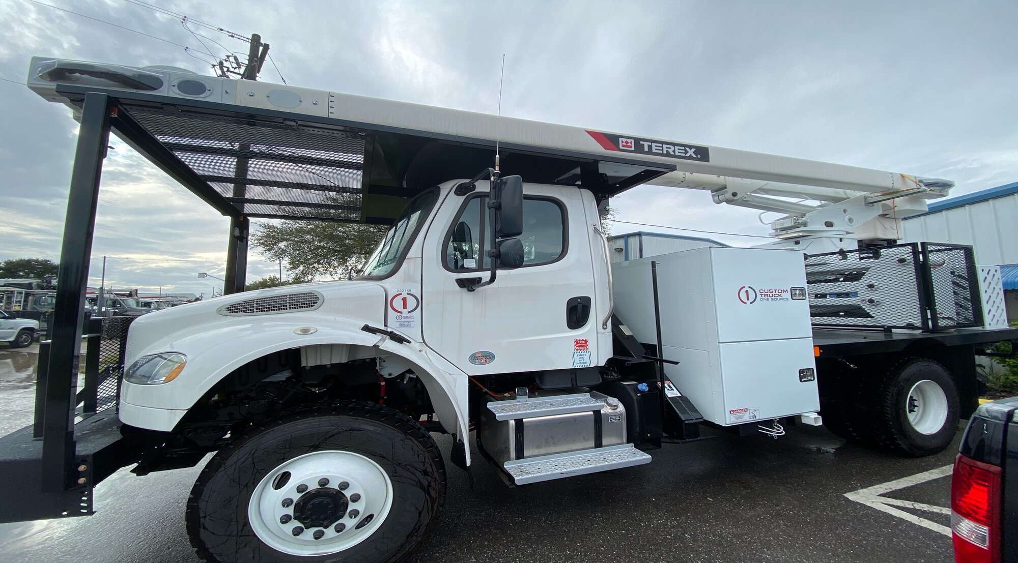 White bucket truck with boom lift in company yard