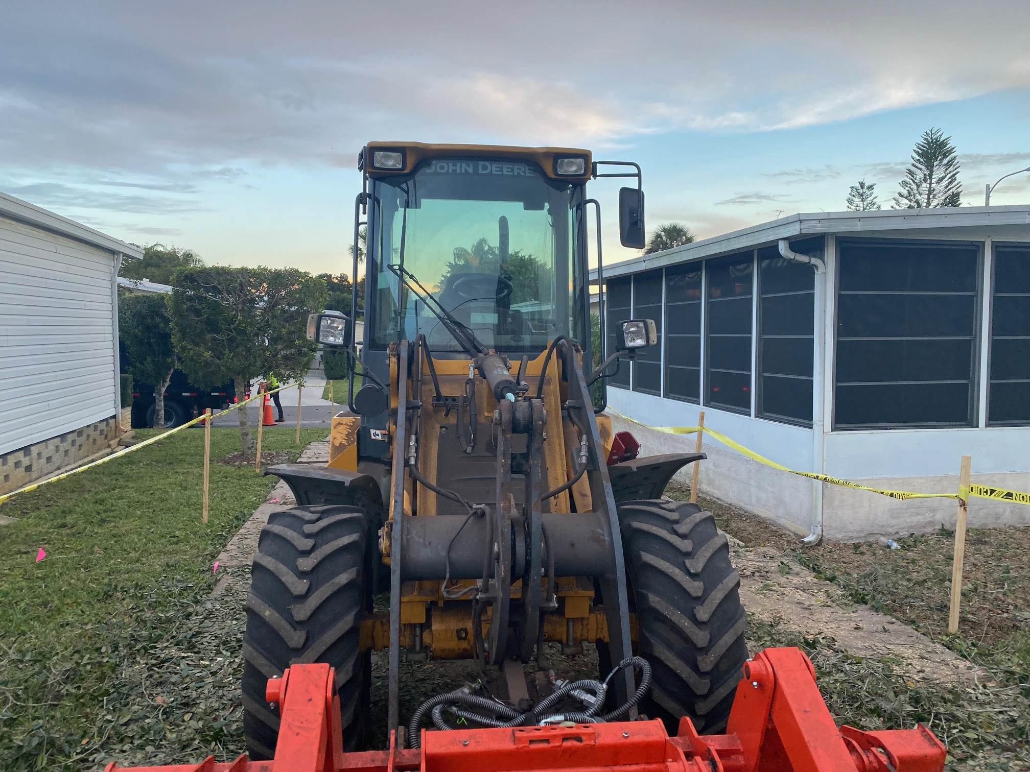 John Deere loader transporting brush and logs